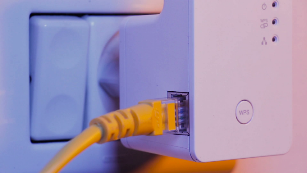  A close-up image of a Wi-Fi extender plugged into a wall socket, with an Ethernet cable plugged into the extender.